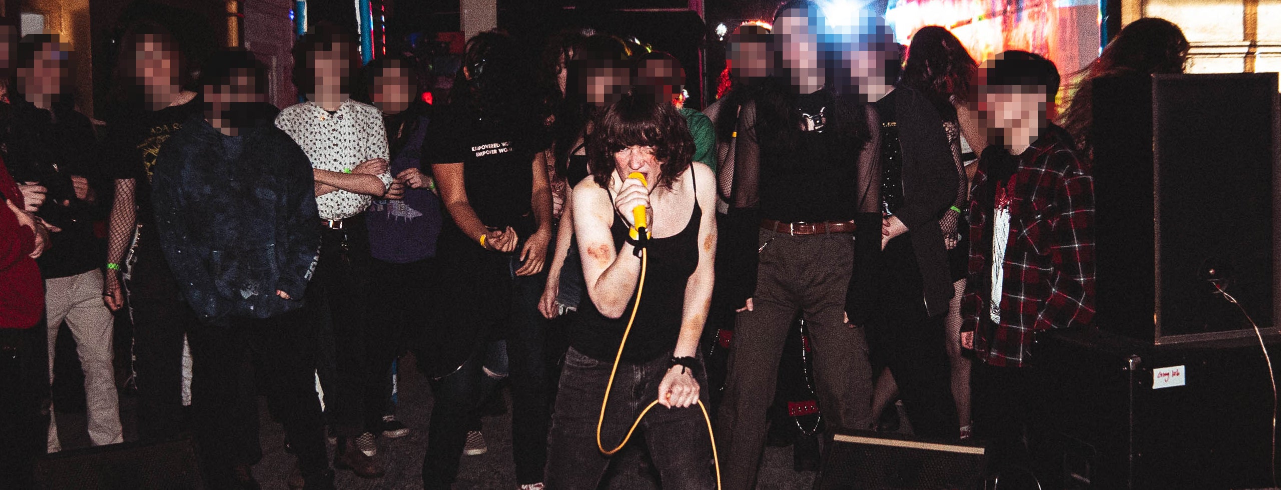 Ada Rook performing on stage with a microphone, surrounded by the audience in a dark setting. Photo by wmmd._