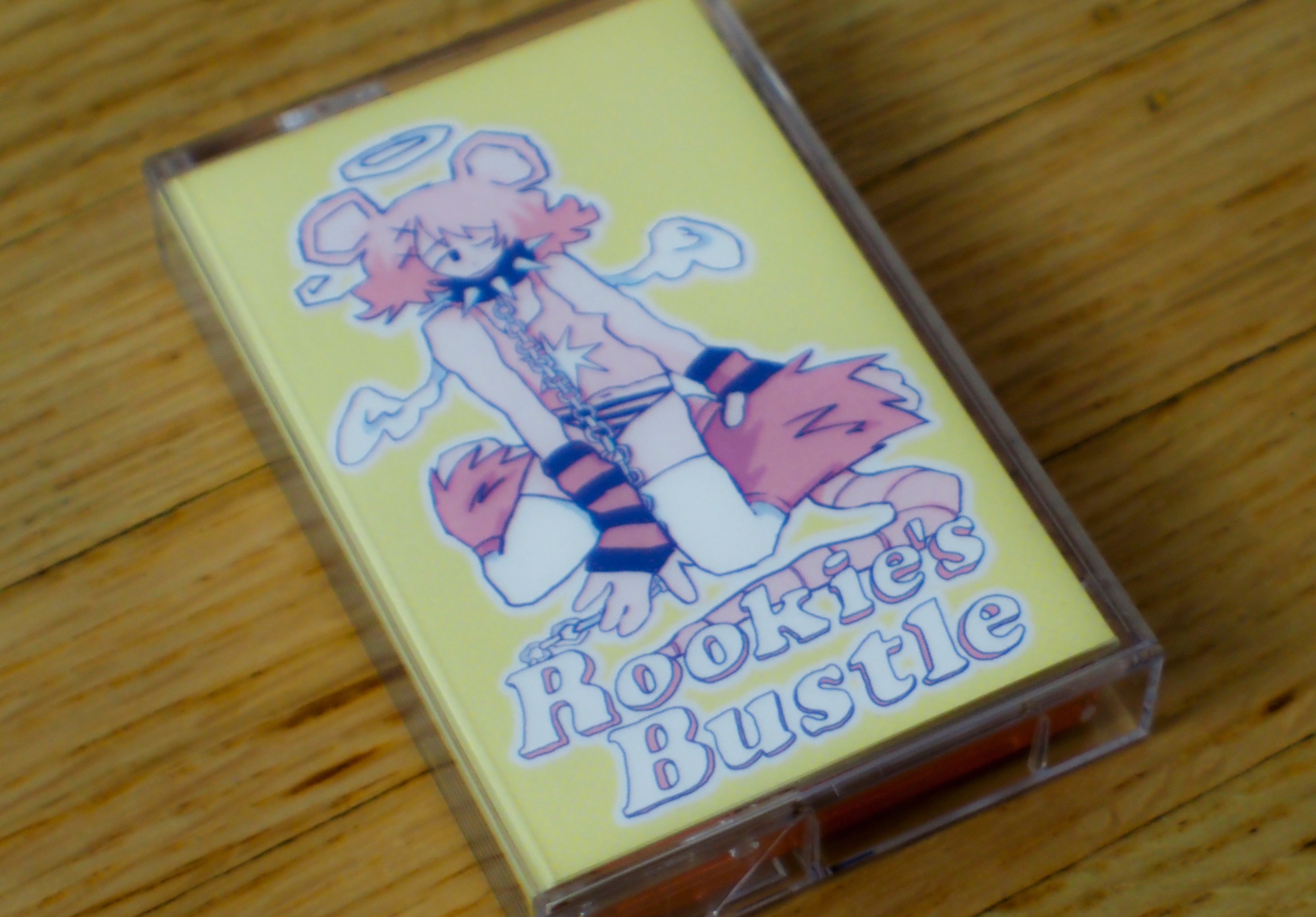 "Rookie's Bustle" cassette tape with a colorful illustration on a wooden surface