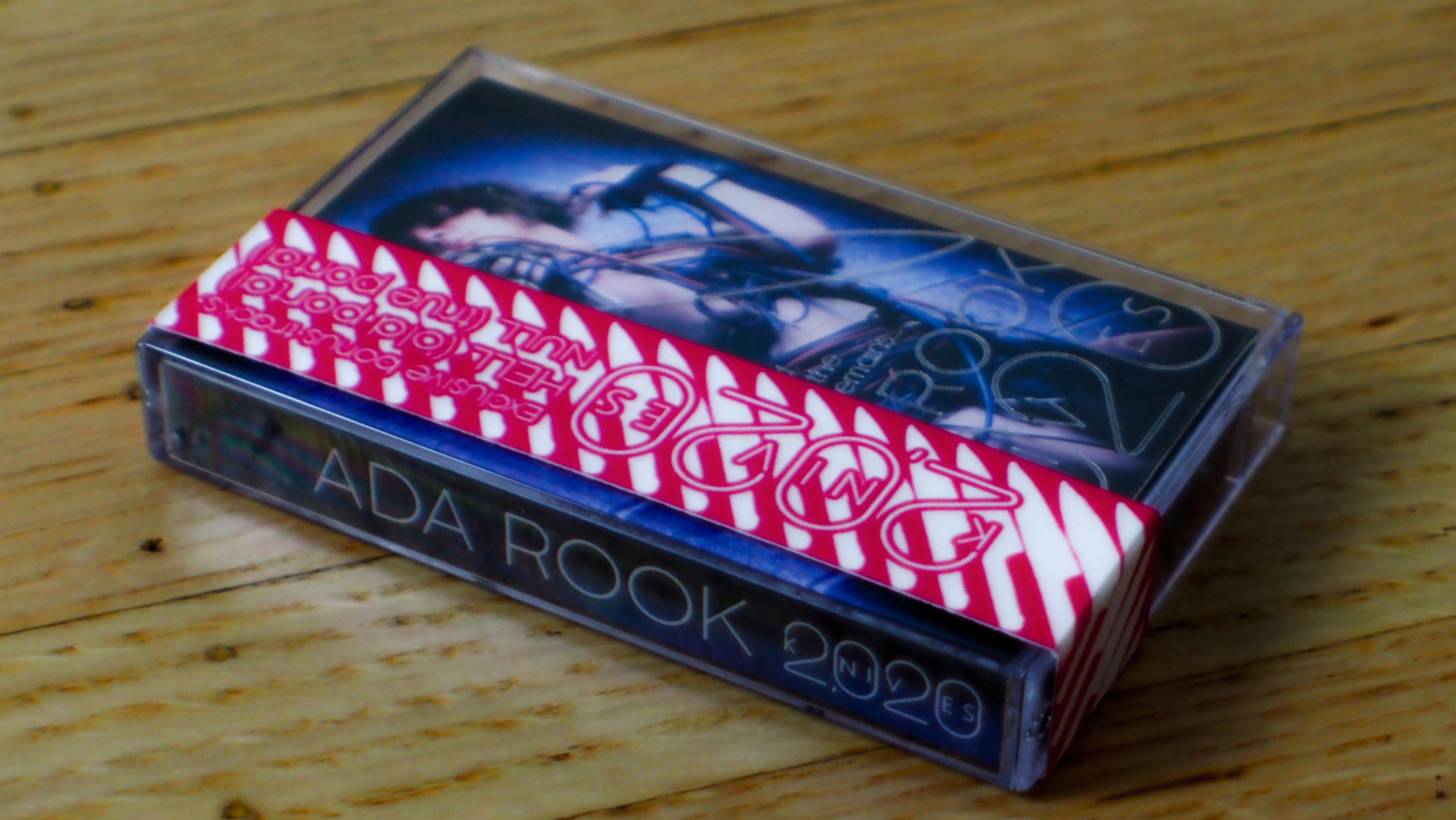 Cassette tape titled "2020 Knives" with a red and white striped design on a wooden surface