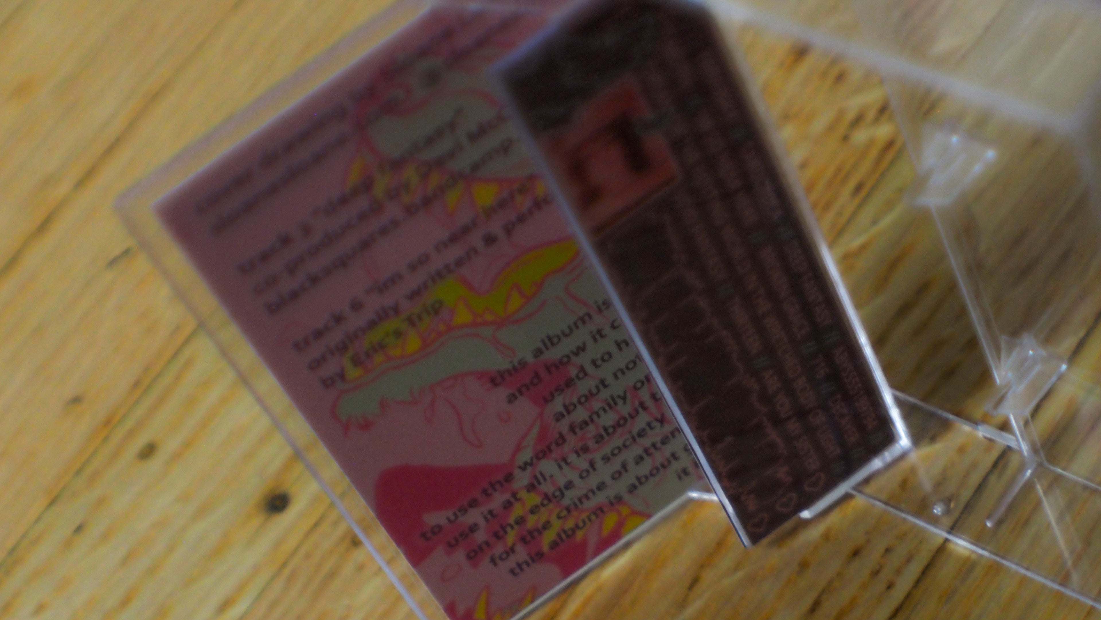 "Shed Blood" cassette case interior with colorful graphics on a wooden surface.
