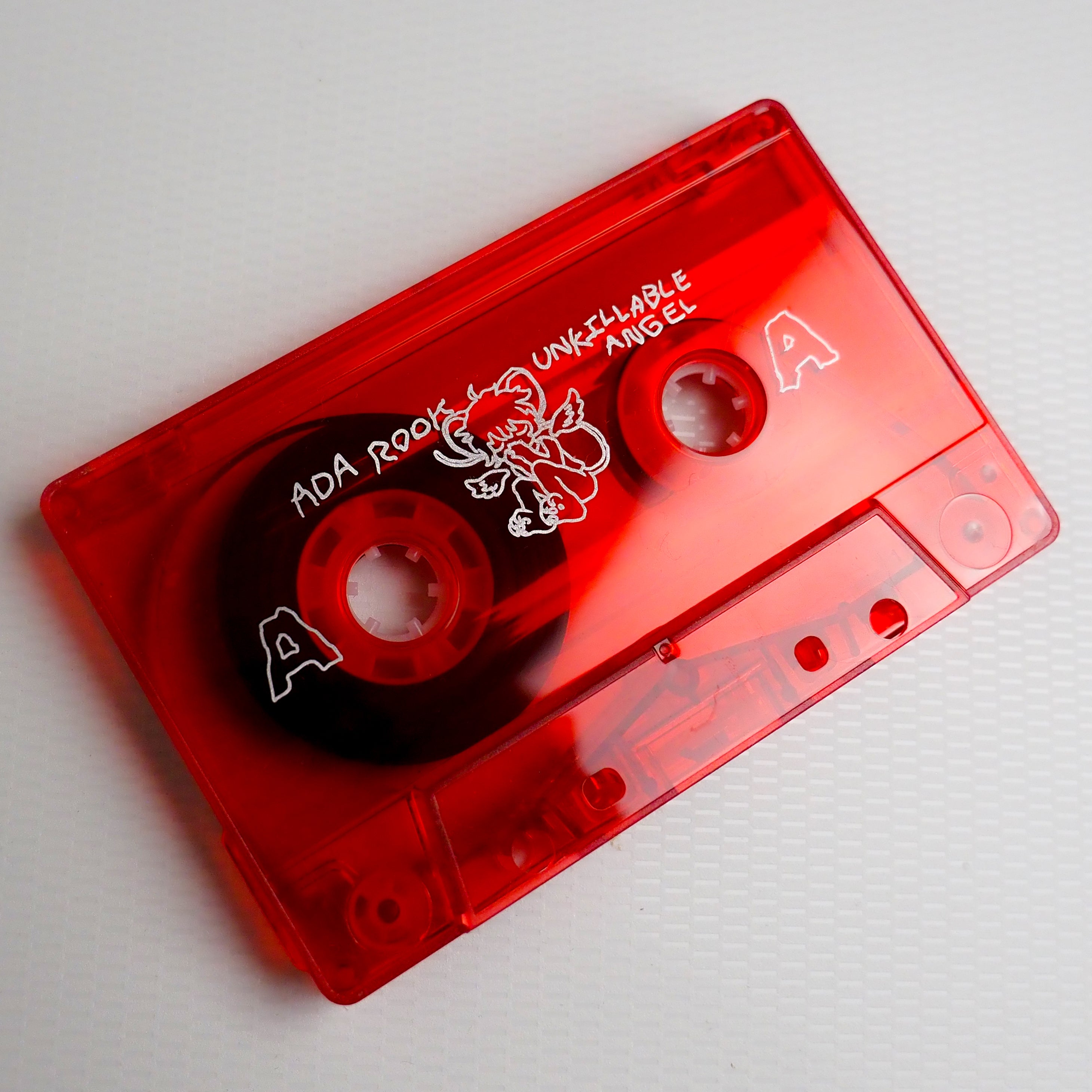 Red cassette tape alone for "Unkillable Angel" on a light gray background