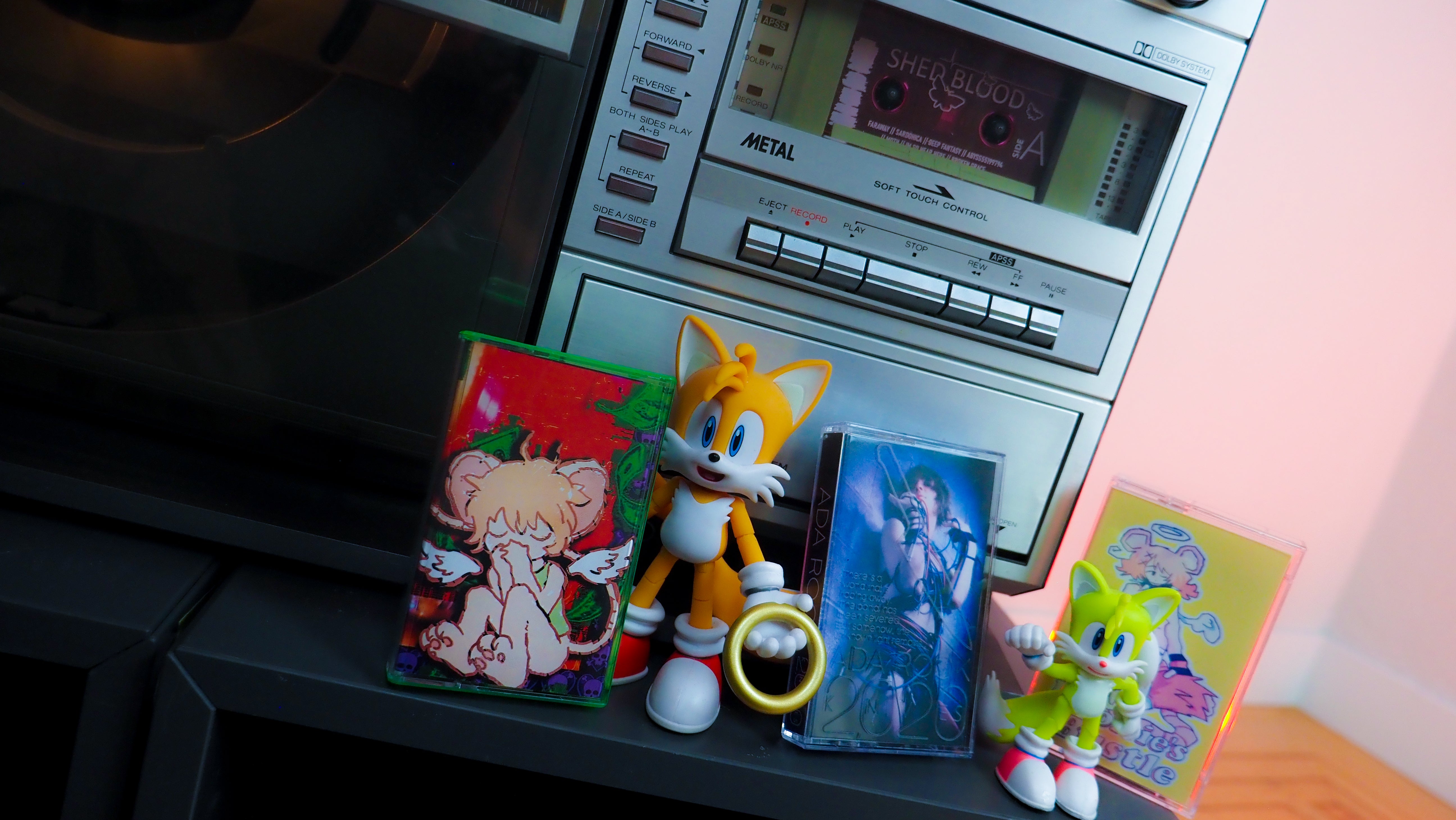 Tails the Fox helpfully presenting three cassette cases for Ada Rook albums.